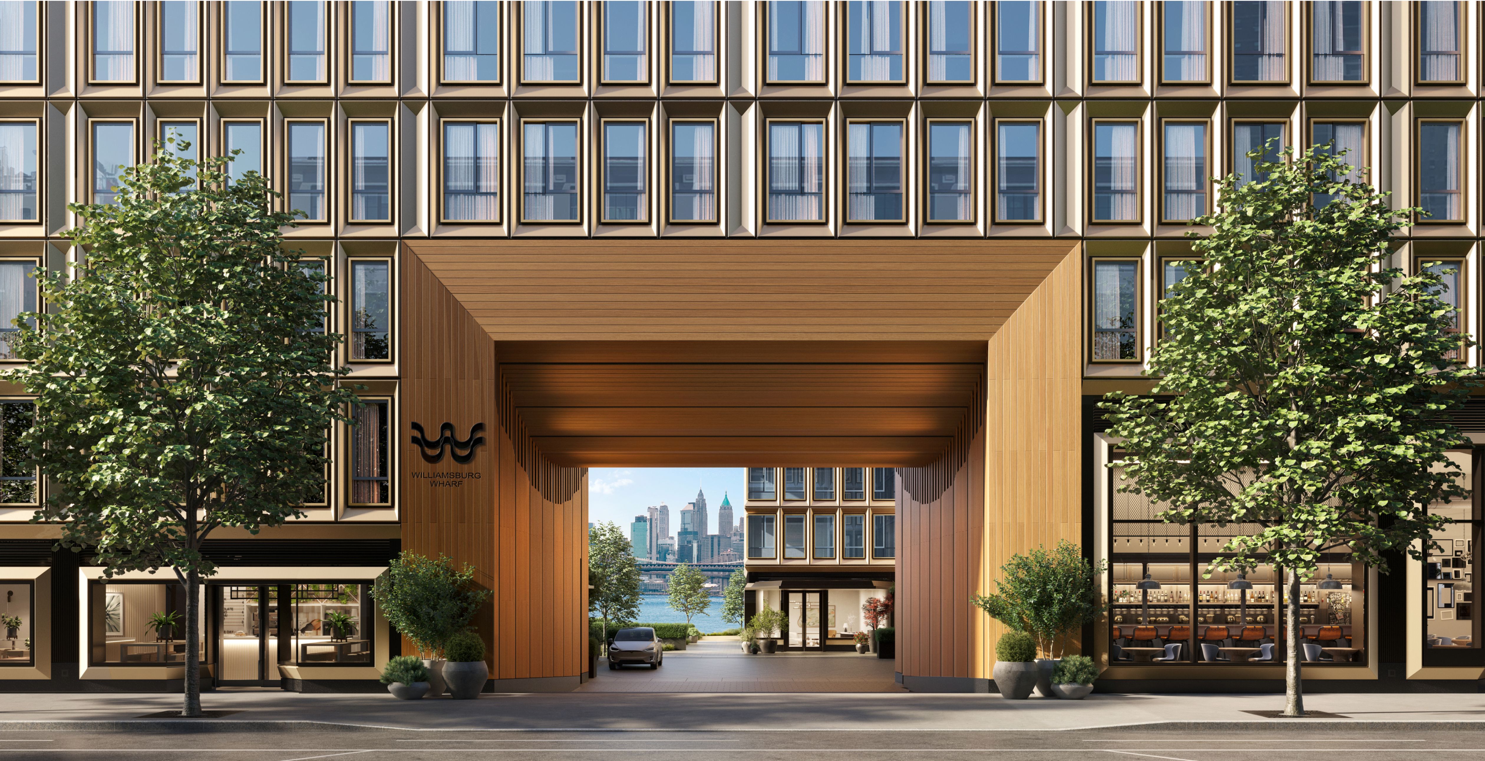 Williamsburg Wharf entrance with modern architecture, landscaped grounds, and views of the East River and Manhattan skyline in Brooklyn, NY.