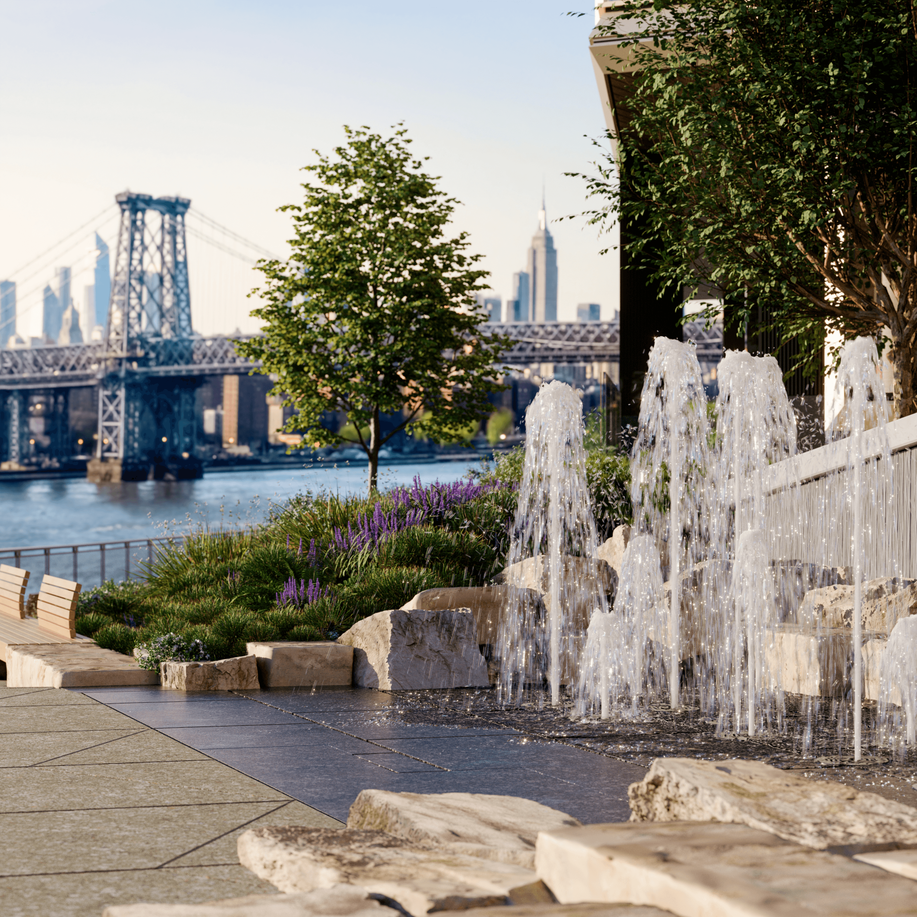 Water fountains and landscaped green space at the Williamsburg Wharf community in Brooklyn, NY, with views of the East River and Williamsburg Bridge.