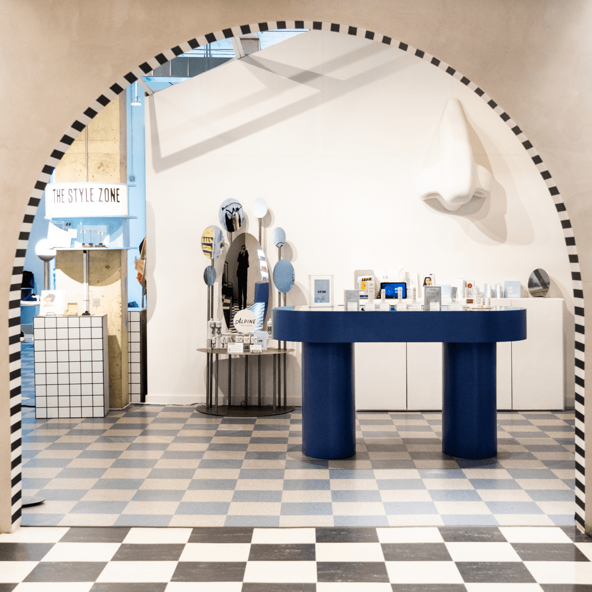 Retail display in Williamsburg, Brooklyn, featuring a blue counter, mirrors, and various products, framed by a black and white striped archway.