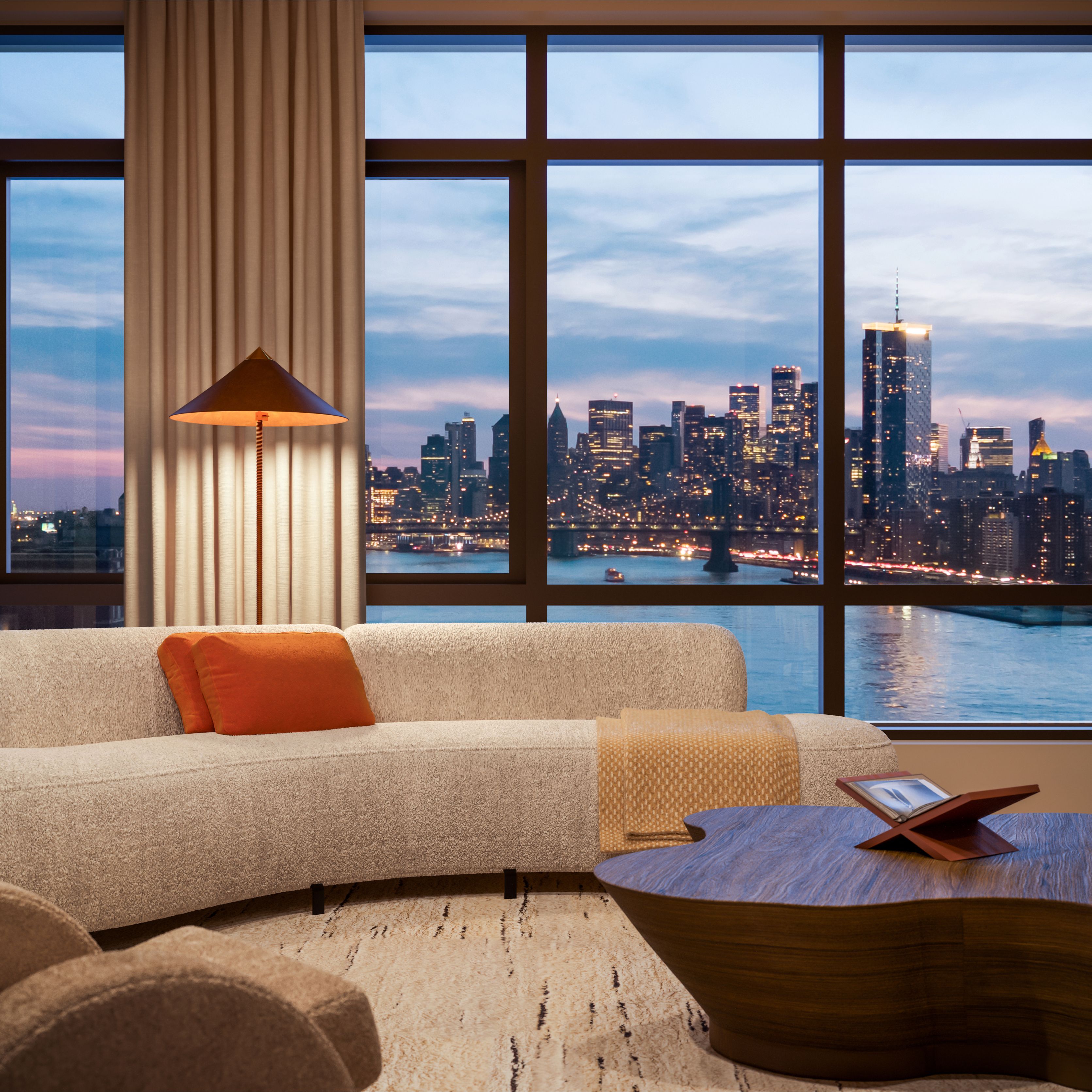 Williamsburg condominium living room at One Williamsburg Wharf with floor-to-ceiling windows showcasing panoramic views of the East River and illuminated Manhattan skyline.